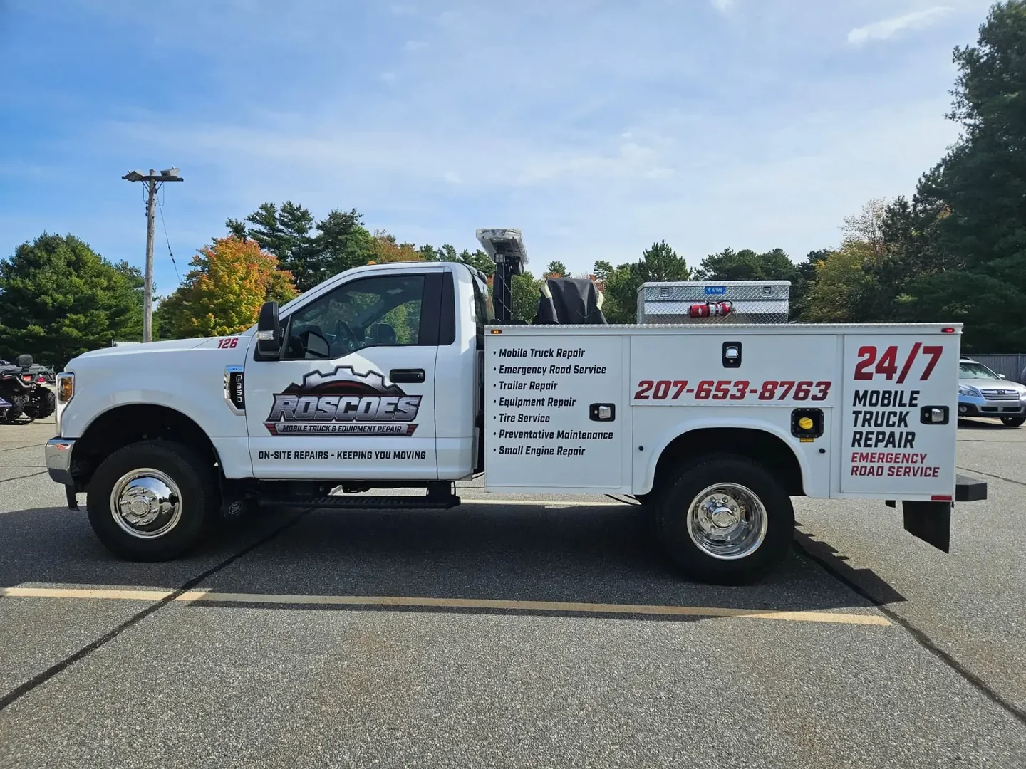 Roscoe's white service truck with its repair service list and phone number on the side, parked in a lot
